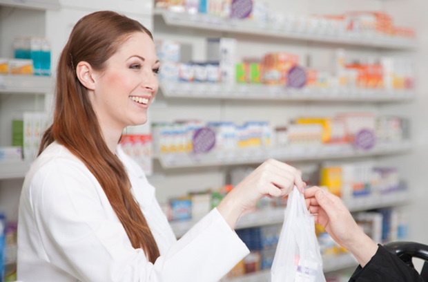 Female pharmacist providing bag of medications to patient